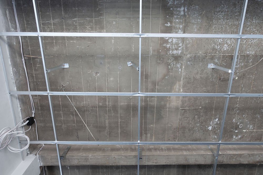 Esempio di pendinatura irregolare di un controsoffitto ancorato a parete e soffitto con un uso improprio di parti residue di telaio. Viti e tasselli di ancoraggio non idonei
