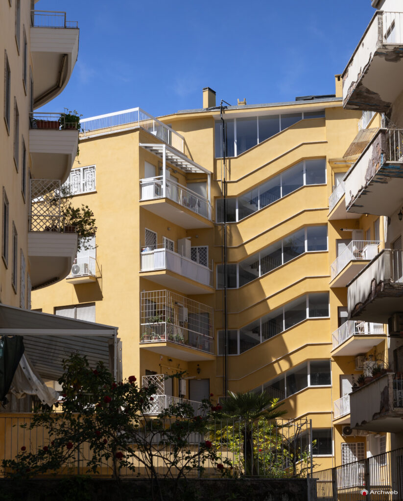 Side facade of the Cassiopea building in Via Archimede, with the windows of the main stairwell in the foreground