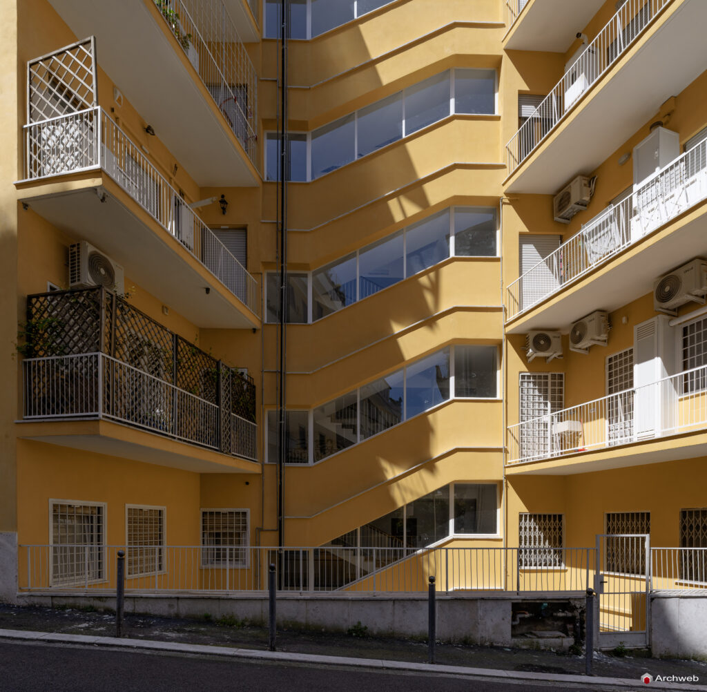Side facade of the Cassiopea building in Via Archimede, with the windows of the main stairwell in the foreground