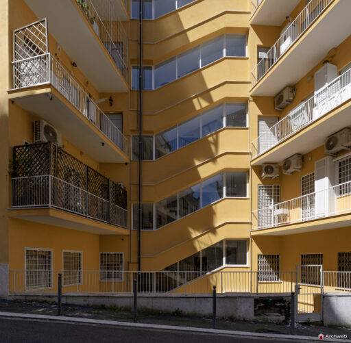 Side facade of the Cassiopea building in Via Archimede, with the windows of the main stairwell in the foreground