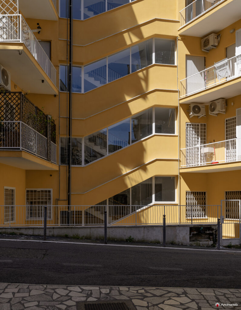 Side facade of the Cassiopea building in Via Archimede, with the windows of the main stairwell in the foreground